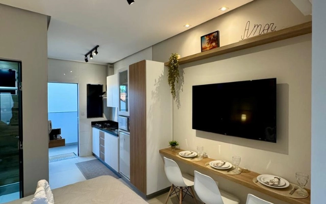 Sala de estar integrada com cozinha e TV no Flat 201 da Ahava Stays em Montes Claros MG.